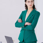 A professional woman wearing a sophisticated emerald green tailored blazer, featuring a slim-fit silhouette, notched lapels, and flap pockets, styled elegantly with a patterned silk scarf for a corporate office look.