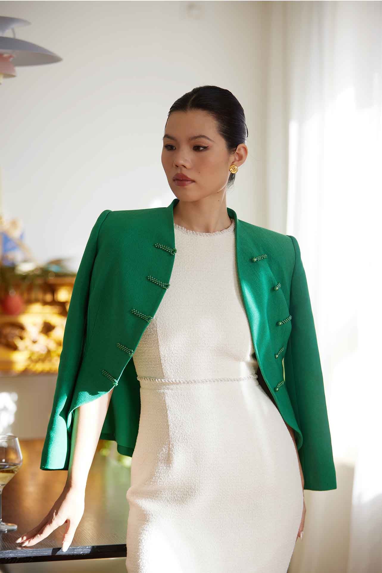 A professional woman wearing a stunning vibrant green blazer, featuring a traditional mandarin collar and elegant frog button detailing for a modern oriental-inspired executive look.