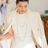 A professional woman wearing a sophisticated cream white double-breasted tweed blazer, featuring elegant gold buttons, a tailored slim fit, and classic flap pockets for a polished executive look.