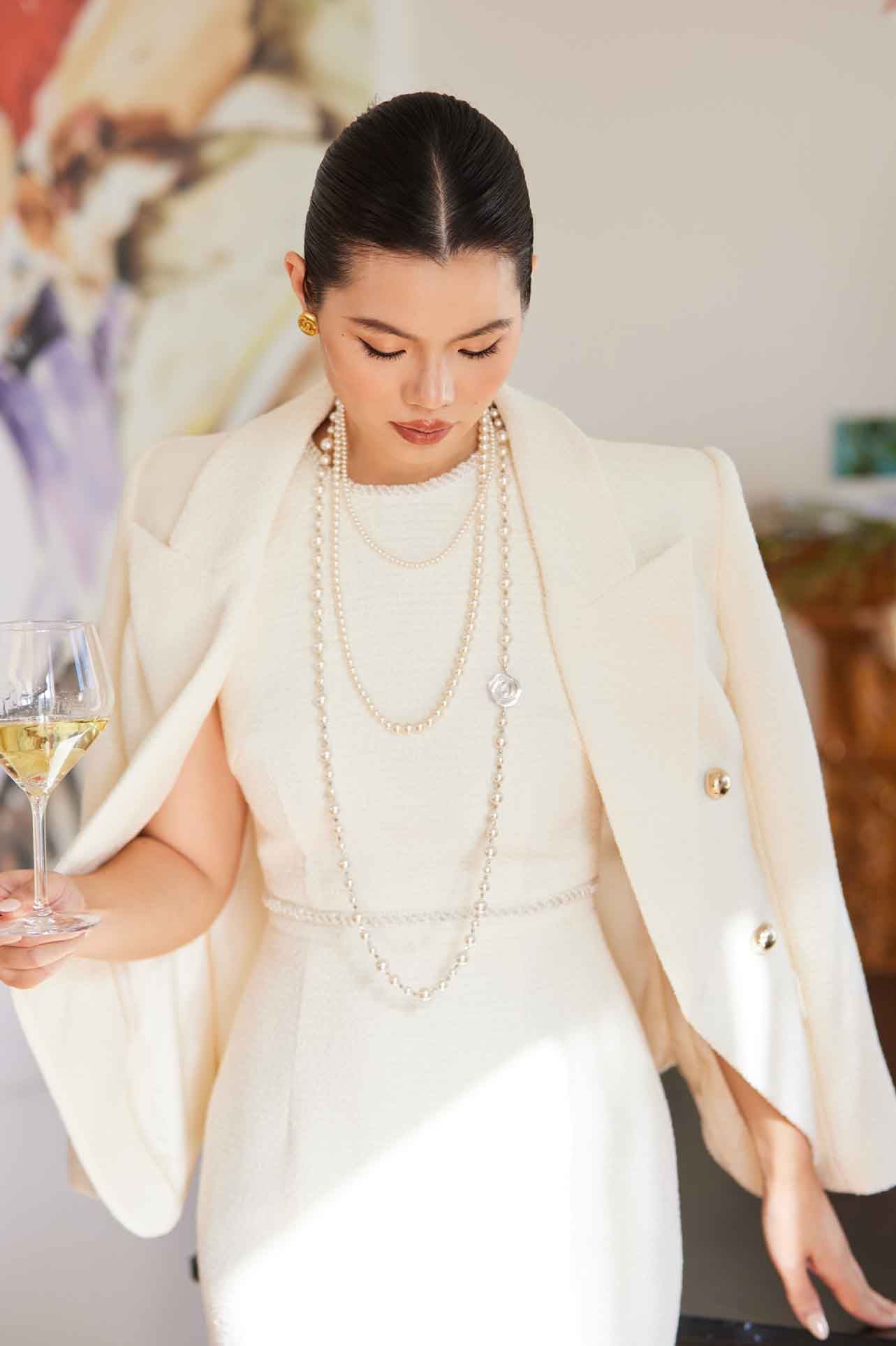 A professional woman wearing a sophisticated cream white double-breasted tweed blazer, featuring elegant gold buttons, a tailored slim fit, and classic flap pockets for a polished executive look.