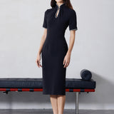 An elegant woman wearing a sophisticated black short-sleeve sheath dress, featuring a traditional mandarin collar with a modern keyhole neckline and delicate beaded trim details for a polished formal look.