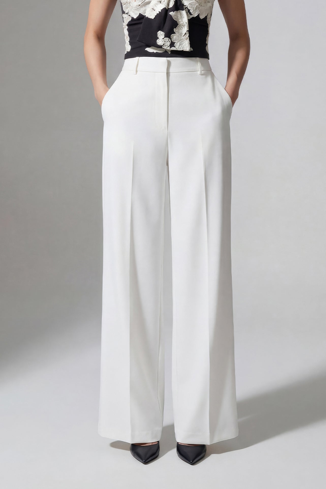 A professional woman wearing sophisticated black high-waisted wide-leg trousers, featuring a flattering high-rise fit and a flowing full-length silhouette for an elegant office look.