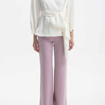 A professional woman wearing sophisticated black high-waisted straight-leg trousers, featuring a tailored silhouette with creased front details for a polished executive office look.