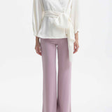 A professional woman wearing sophisticated black high-waisted straight-leg trousers, featuring a tailored silhouette with creased front details for a polished executive office look.