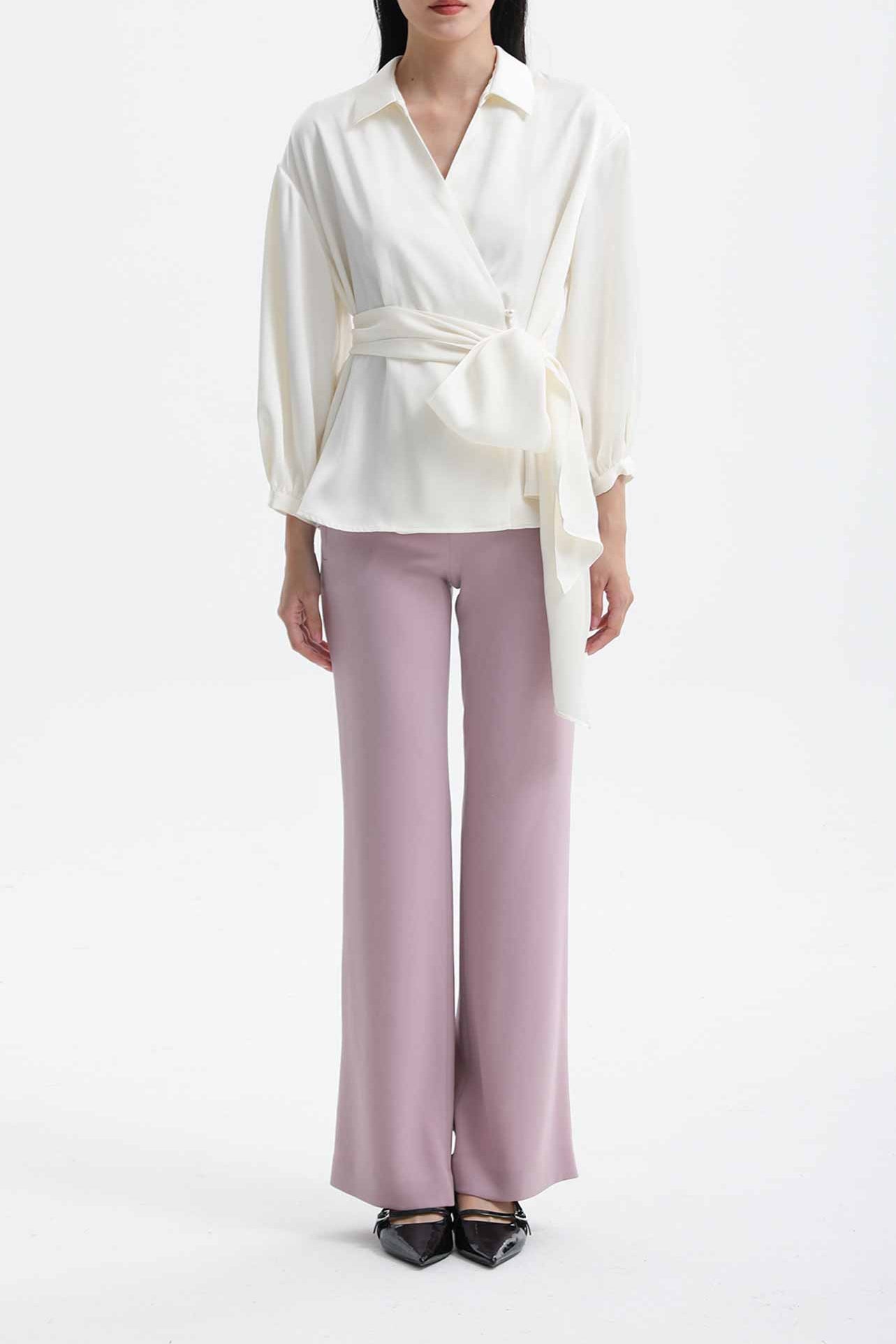 A professional woman wearing sophisticated black high-waisted straight-leg trousers, featuring a tailored silhouette with creased front details for a polished executive office look.