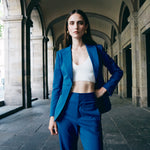 A professional woman wearing sophisticated royal blue high-waisted wide-leg trousers, featuring a tailored loose-fit silhouette for a modern and vibrant executive office look.