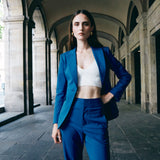 A professional woman wearing sophisticated royal blue high-waisted wide-leg trousers, featuring a tailored loose-fit silhouette for a modern and vibrant executive office look.