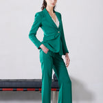 A professional woman wearing sophisticated emerald green high-waisted flare trousers, featuring a tailored slim fit through the hip and a stylish bootcut silhouette for an elegant office look.