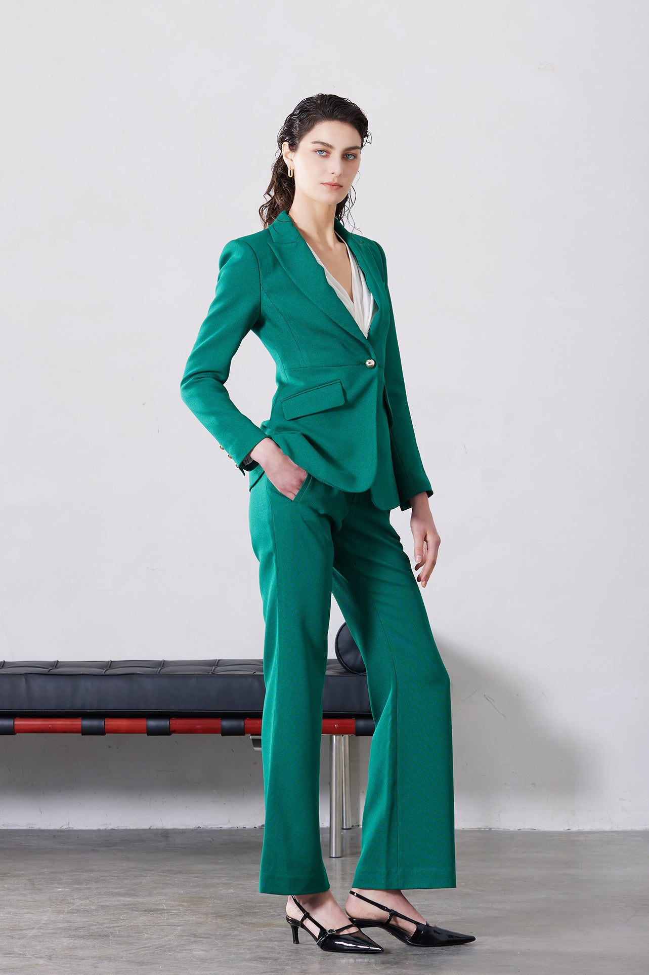 A professional woman wearing sophisticated emerald green high-waisted flare trousers, featuring a tailored slim fit through the hip and a stylish bootcut silhouette for an elegant office look.
