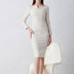 A professional woman wearing a sophisticated black long-sleeve midi dress, featuring a unique notched square neckline and a tailored slim-fit pencil silhouette for a polished executive office look.