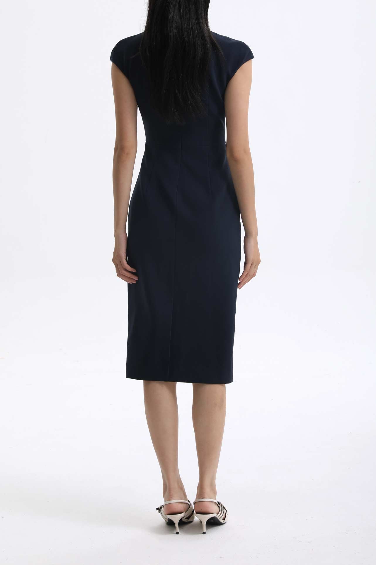 A professional woman wearing a sophisticated navy blue midi dress, featuring an elegant pleated neckline with a subtle keyhole detail and a tailored slim-fit pencil silhouette for a polished executive look.