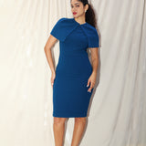 A professional woman wearing a sophisticated teal blue midi dress with an elegant cape-style overlay and structured shoulders, perfect for formal executive events and ceremonial occasions.