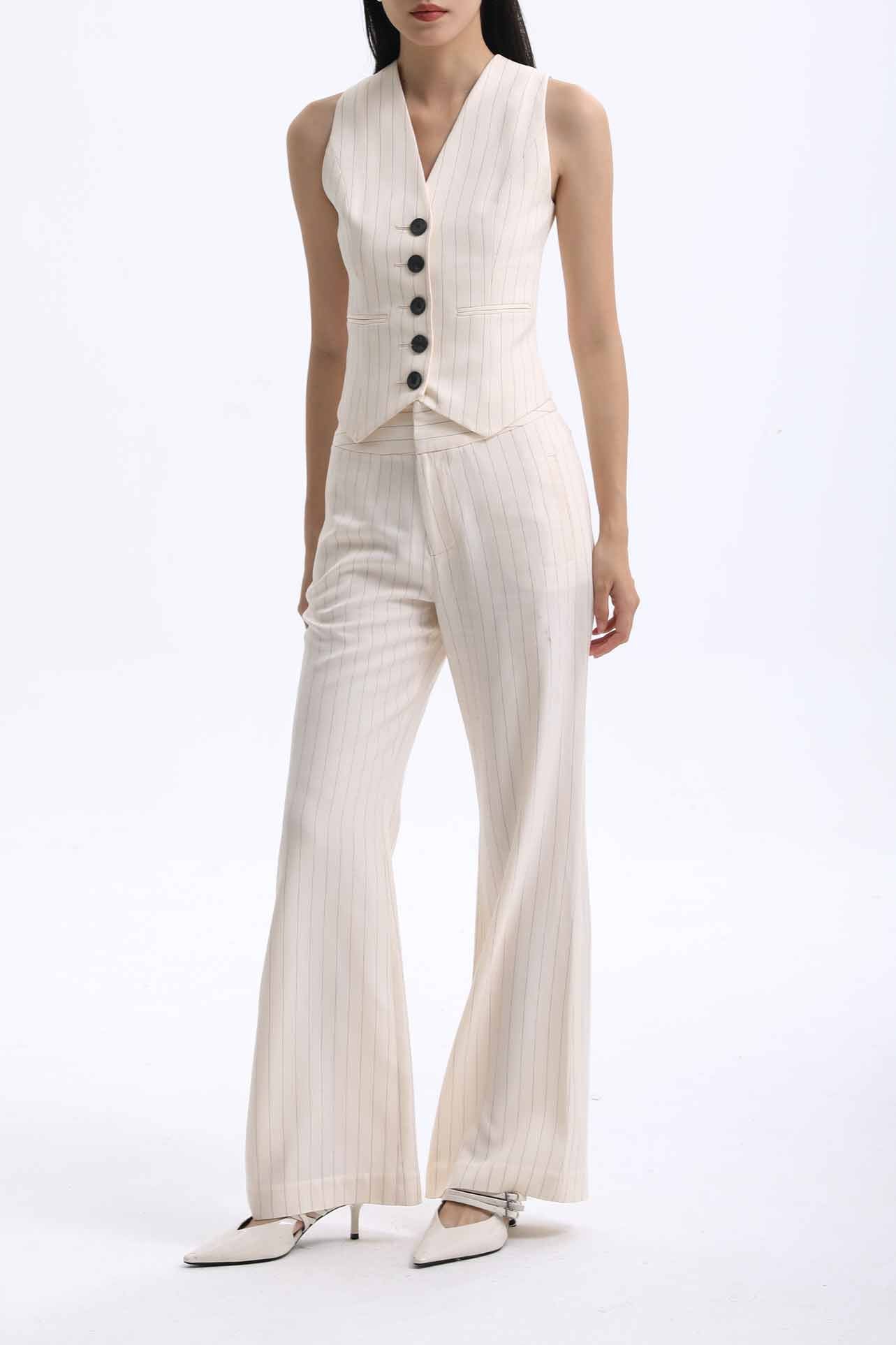 A professional woman wearing sophisticated cream pinstripe high-waisted wide-leg trousers, featuring a tailored loose-fit silhouette and styled with a pearl handbag for an elegant old money office look.