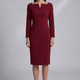 A professional woman wearing a sophisticated black long-sleeve midi dress, featuring a unique notched square neckline and a tailored slim-fit pencil silhouette for a polished executive office look.