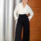 A professional woman wearing sophisticated black high-waisted wide-leg trousers, featuring a flattering high-rise fit and a flowing full-length silhouette for an elegant office look.