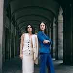 A professional woman wearing sophisticated royal blue high-waisted wide-leg trousers, featuring a tailored loose-fit silhouette for a modern and vibrant executive office look.