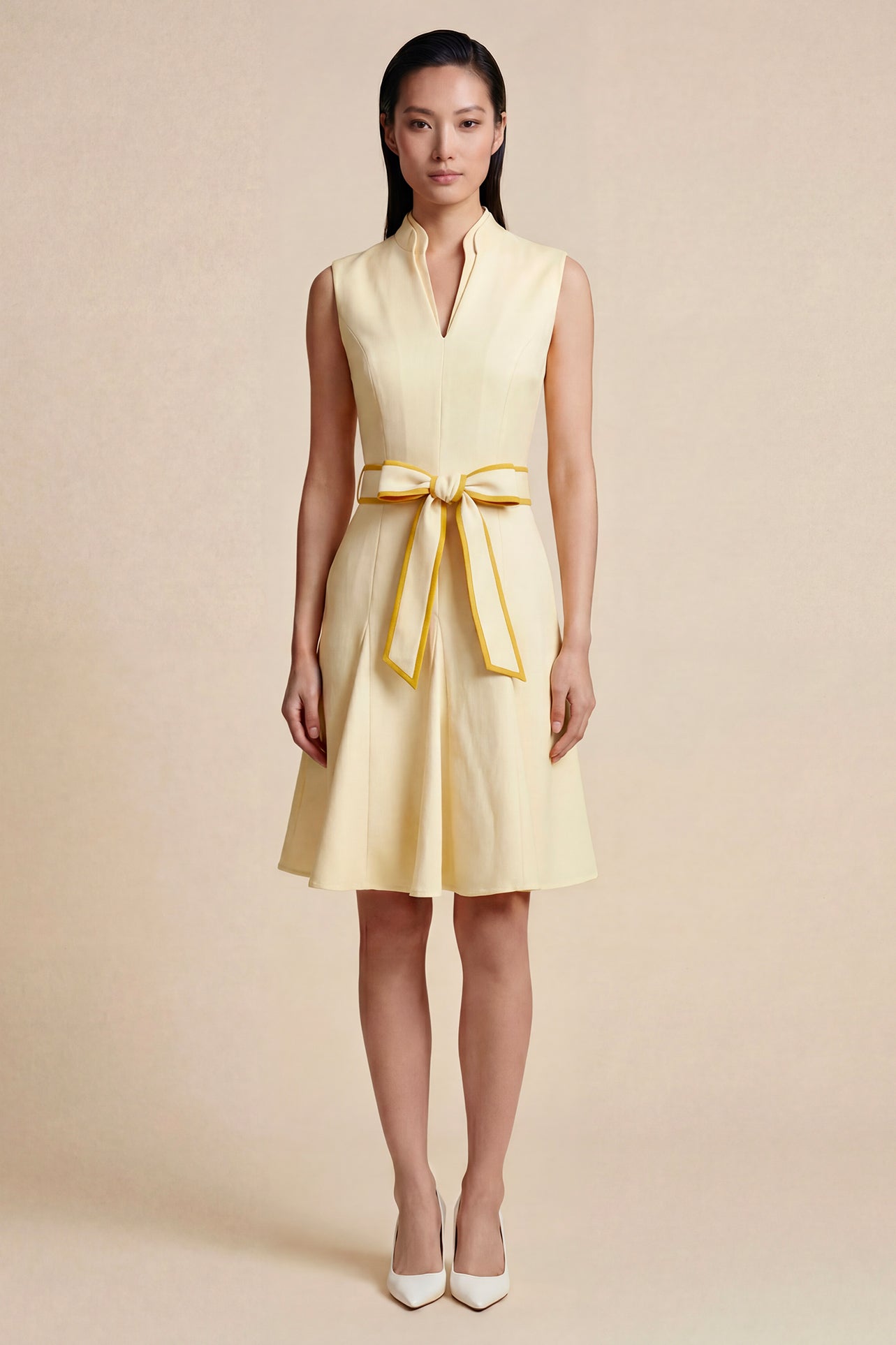 A side-by-side comparison of an elegant pale yellow sleeveless dress in two lengths, featuring a sophisticated mandarin collar, a stylish bow tie-waist, and a pleated A-line skirt for a classic feminine look