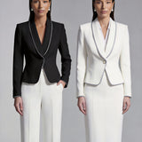 Two elegant professional women modeling high-end monochrome executive suits, one in a black blazer with white piping and wide-leg trousers, the other in a white blazer with dark trim and a matching pencil skirt.