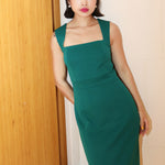A professional woman wearing a sophisticated emerald green sleeveless dress, featuring a classic square neckline and a flattering tailored sheath silhouette for an elegant executive look.