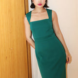 A professional woman wearing a sophisticated emerald green sleeveless dress, featuring a classic square neckline and a flattering tailored sheath silhouette for an elegant executive look.