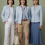 A professional woman modeling a sophisticated light blue tailored blazer with white buttons, perfectly paired with a contrasting navy blue pleated midi skirt for a refined business look.