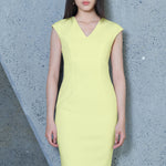 A professional woman wearing a sophisticated solid white sleeveless sheath dress, featuring a flattering V-neckline and an elegant thin black belt with a gold buckle for a polished executive office look.