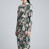 A professional woman wearing a sophisticated dark green wrap dress with a vibrant pink floral print, featuring long sleeves and a slimming waist-tie for an elegant spring look.