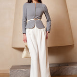 A professional woman wearing a sophisticated grey pinstripe zip-up blazer, featuring a thin white belt with a gold buckle and a tailored slim fit for a modern office look.