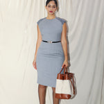 A professional woman wearing a sophisticated grey sleeveless sheath dress, featuring a tailored slim-fit silhouette and an elegant thin black belt with a gold buckle for a polished executive office look.