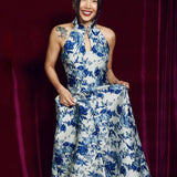 A stunning modern oriental gala dress featuring a classic blue and white porcelain floral print, an elegant halter neck with keyhole detail, and a voluminous A-line full skirt for a sophisticated formal look.