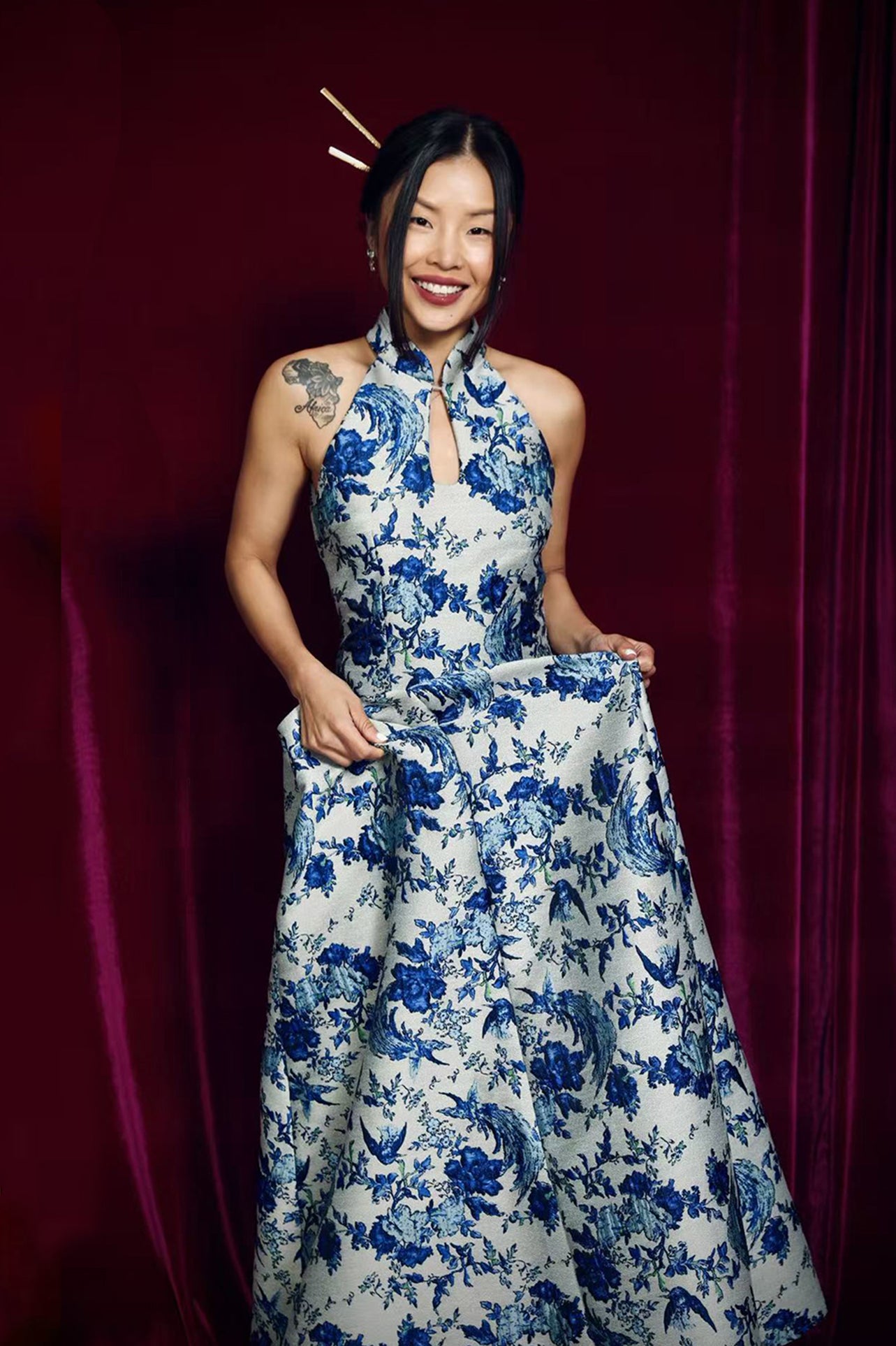A stunning modern oriental gala dress featuring a classic blue and white porcelain floral print, an elegant halter neck with keyhole detail, and a voluminous A-line full skirt for a sophisticated formal look.
