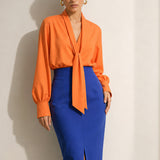 A style collection of three models presenting elegant dopamine office wear; the left in a white bow-tie blouse with a mustard yellow front-slit midi skirt, the center wearing a blue striped pussy-bow shirt with a straw hat and white wide-leg trousers, and the right in a vibrant orange satin blouse with a royal blue pencil skirt
