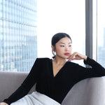 A professional woman wearing sophisticated high-waisted wide-leg pinstripe trousers in charcoal black, featuring a tailored slimming fit for a powerful executive office look.