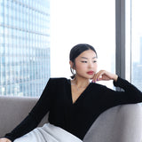 A professional woman wearing sophisticated high-waisted wide-leg pinstripe trousers in charcoal black, featuring a tailored slimming fit for a powerful executive office look.