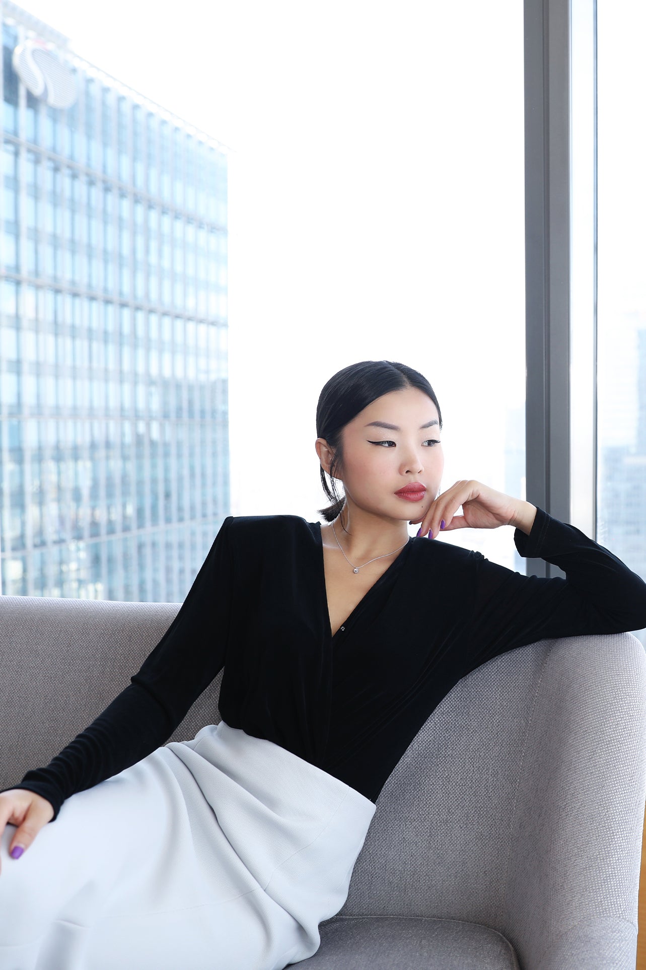 A professional woman wearing sophisticated high-waisted wide-leg pinstripe trousers in charcoal black, featuring a tailored slimming fit for a powerful executive office look.