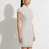 A professional woman modeling an elegant white lace modern qipao dress, featuring an intricate eyelet textured fabric, a sophisticated mandarin collar with a traditional knot button, and slimming cap sleeves.