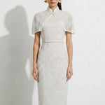 A collection of two professional models wearing elegant white lace midi dresses; the left showcasing a minimalist sleeveless bateau neck sheath dress, and the right featuring a modern Chinese qipao with a sophisticated capelet sleeve detail and traditional mandarin collar.