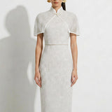 A collection of two professional models wearing elegant white lace midi dresses; the left showcasing a minimalist sleeveless bateau neck sheath dress, and the right featuring a modern Chinese qipao with a sophisticated capelet sleeve detail and traditional mandarin collar.