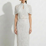 A professional woman modeling an elegant white lace halter neck modern qipao dress, featuring a sophisticated mandarin collar with keyhole detail and an intricate eyelet embroidered fabric for a quiet luxury look.