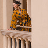 A beautiful woman modeling an elegant mustard yellow modern Chinese jacket, featuring intricate blue phoenix embroidery, a sophisticated mandarin collar, and wide kimono sleeves with a matching waist tie.