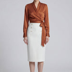 A professional woman wearing a high-end white silk wrap blouse with a side-tie detail, paired with a tailored black high-waisted pencil skirt for a sophisticated executive office look.