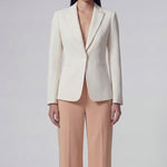 A professional woman wearing sophisticated apricot-colored high-waisted straight-leg trousers, featuring a unique pointed waistband design for a tailored executive office look.