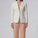 A professional woman wearing sophisticated apricot-colored high-waisted straight-leg trousers, featuring a unique pointed waistband design for a tailored executive office look.