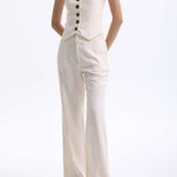 A professional woman wearing sophisticated cream pinstripe high-waisted wide-leg trousers, featuring a tailored loose-fit silhouette and styled with a pearl handbag for an elegant old money office look.