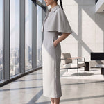 A style comparison of two elegant tailored office sheath midi dresses; the left showcasing a structured vibrant purple dress with a collared capelet sleeve design, and the right featuring a minimalist light grey sleeveless dress with subtle pleated neckline and side pockets.