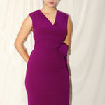A professional woman wearing a sophisticated magenta v-neck sleeveless midi dress, featuring a tailored slim-fit pencil silhouette for a polished executive office or cocktail look.