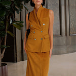 A chic professional woman wearing a tailored camel double-breasted longline suit vest featuring classic notch lapels and flap pockets, layered over a soft beige turtleneck sweater for a sophisticated quiet luxury look.
