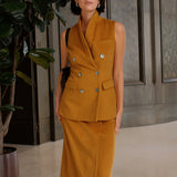 A chic professional woman wearing a tailored camel double-breasted longline suit vest featuring classic notch lapels and flap pockets, layered over a soft beige turtleneck sweater for a sophisticated quiet luxury look.