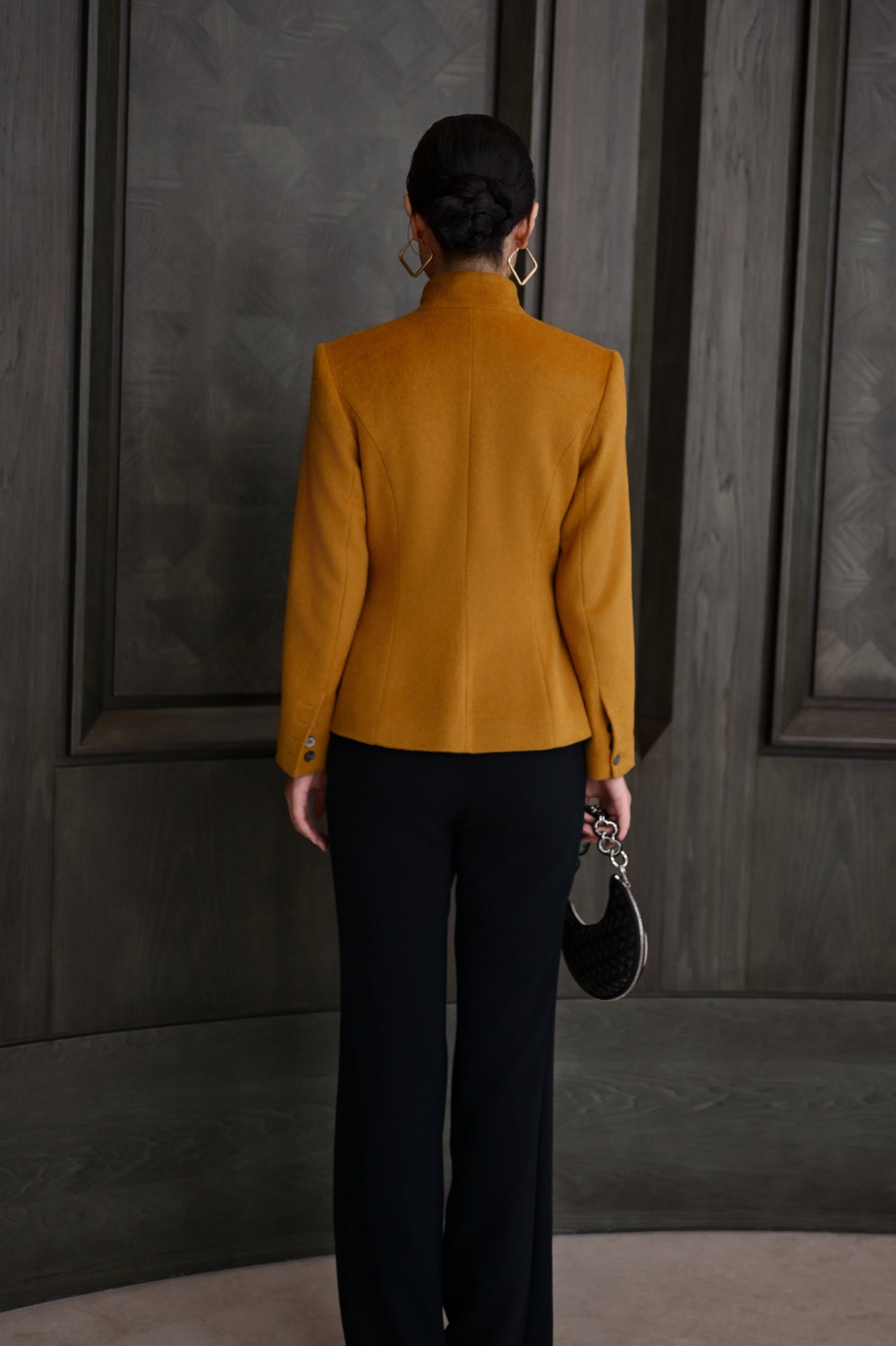 A chic professional Asian woman wearing a luxurious camel wool tailored jacket featuring a sleek stand collar, exposed two-way front zipper, structured shoulders, and an hourglass silhouette paired with a matching skirt.