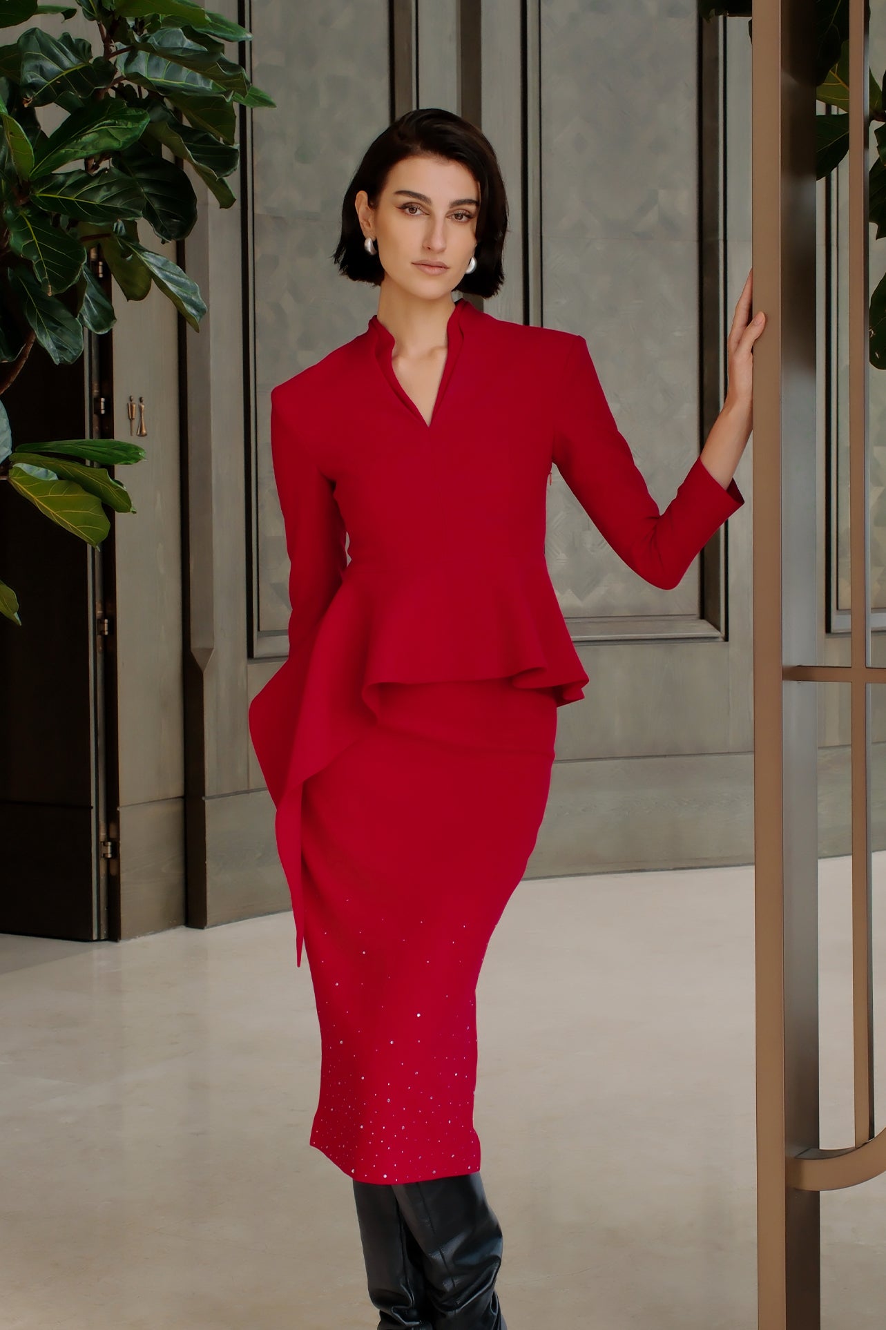 A comparison of three professional women modeling tailored power trouser suits featuring architectural split V-neck jackets with dramatic asymmetrical peplum hems and matching wide-leg trousers in crimson red, deep royal navy, and ice blue.